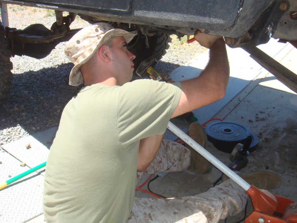 Man working on vehicle undercarriage, close-up on suspension components