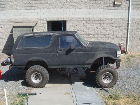 Black 1992 Ford Bronco side view, lifted with large tires