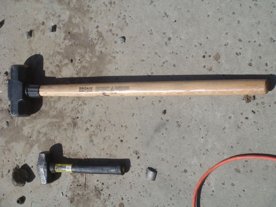 Two sledgehammers, one large and one small, on a concrete surface