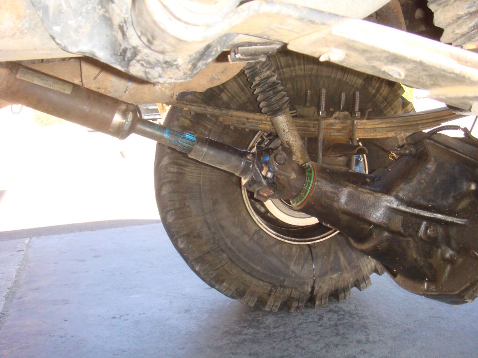Driveshaft connected to rear axle differential with leaf springs and shock absorber visible
