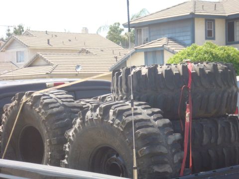 Several large off-road tires stacked in a truck bed