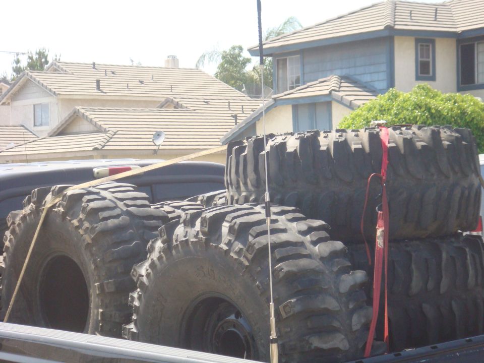 Several large off-road tires stacked in a truck bed