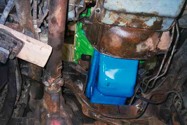 Underside view of engine with freshly painted bright blue oil pan on rusty block