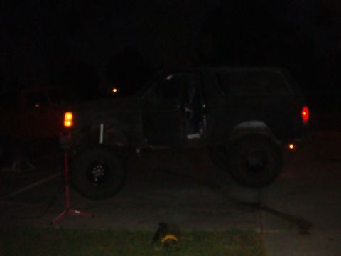 Black SUV lifted on a jack at night, side view