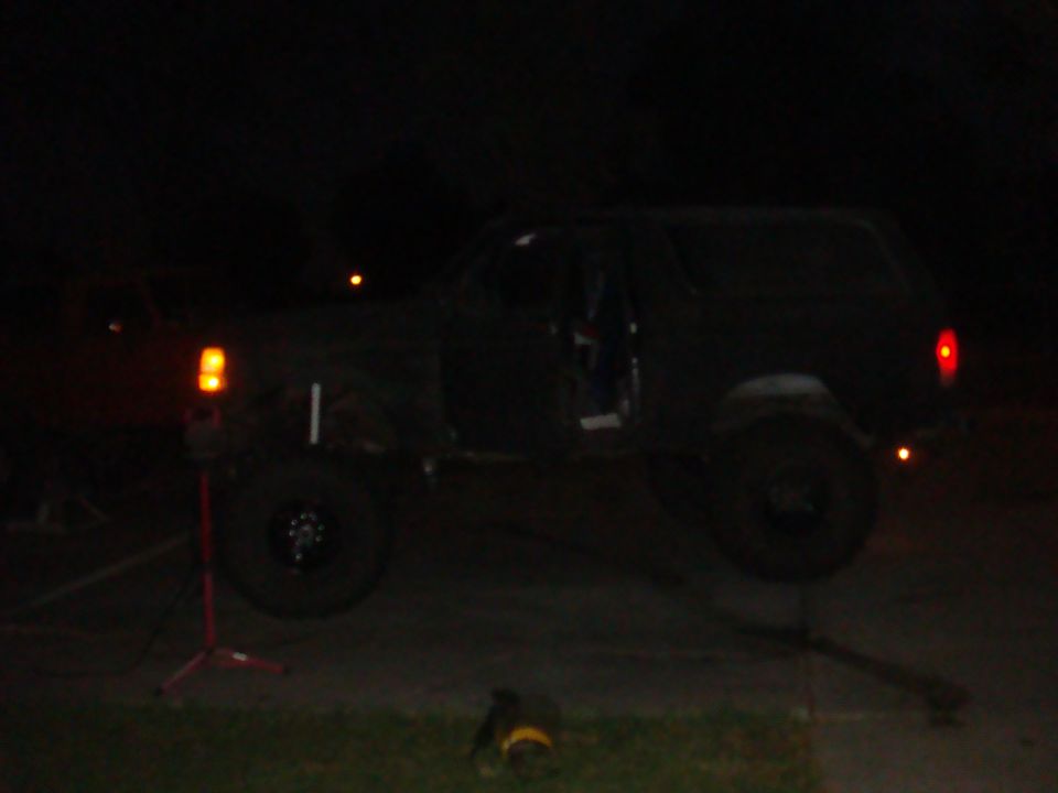 Black SUV lifted on a jack at night, side view