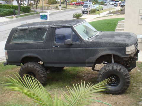 1992 Ford Bronco lifted with large tires, parked on grass