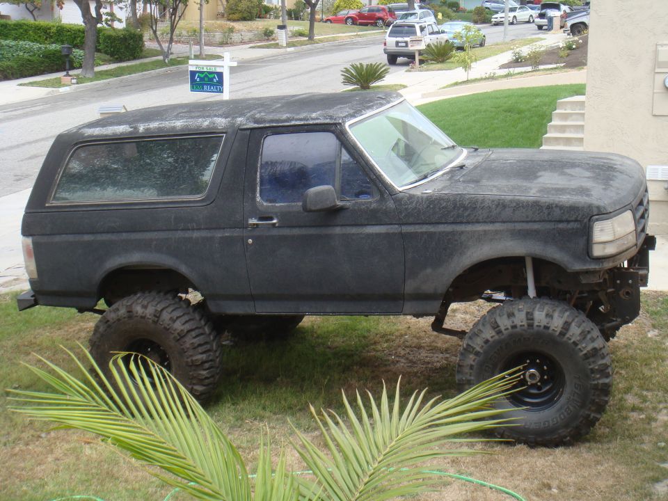 1992 Ford Bronco lifted with large tires, parked on grass