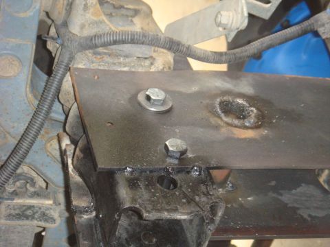 Custom metal bracket welded to vehicle frame with bolts and wiring
