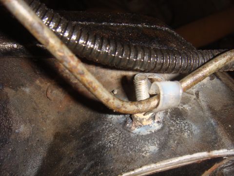 Close-up of a rusted metal component with a hose clamp and bolt
