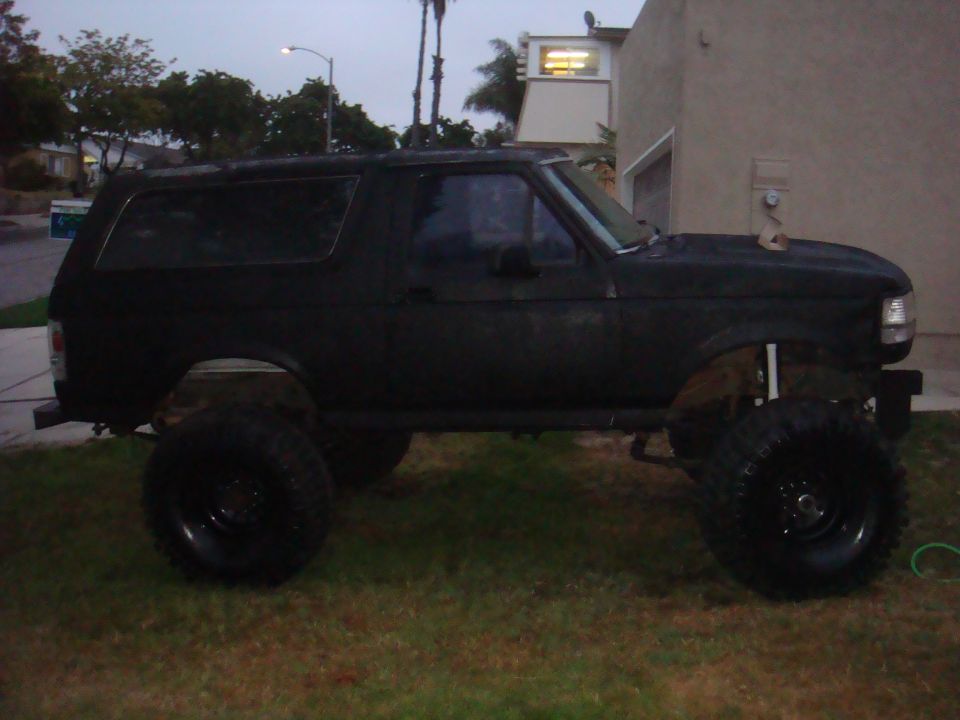 Black 1992 Ford Bronco lifted with large tires, side view