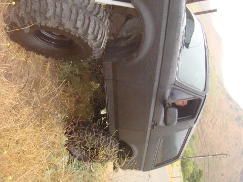 Off-road SUV with large tires parked on a grassy slope