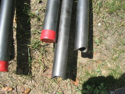 1986 Ford Bronco - Metal tubes with red caps lie on the grass, with a SuperMotors.net watermark visible.