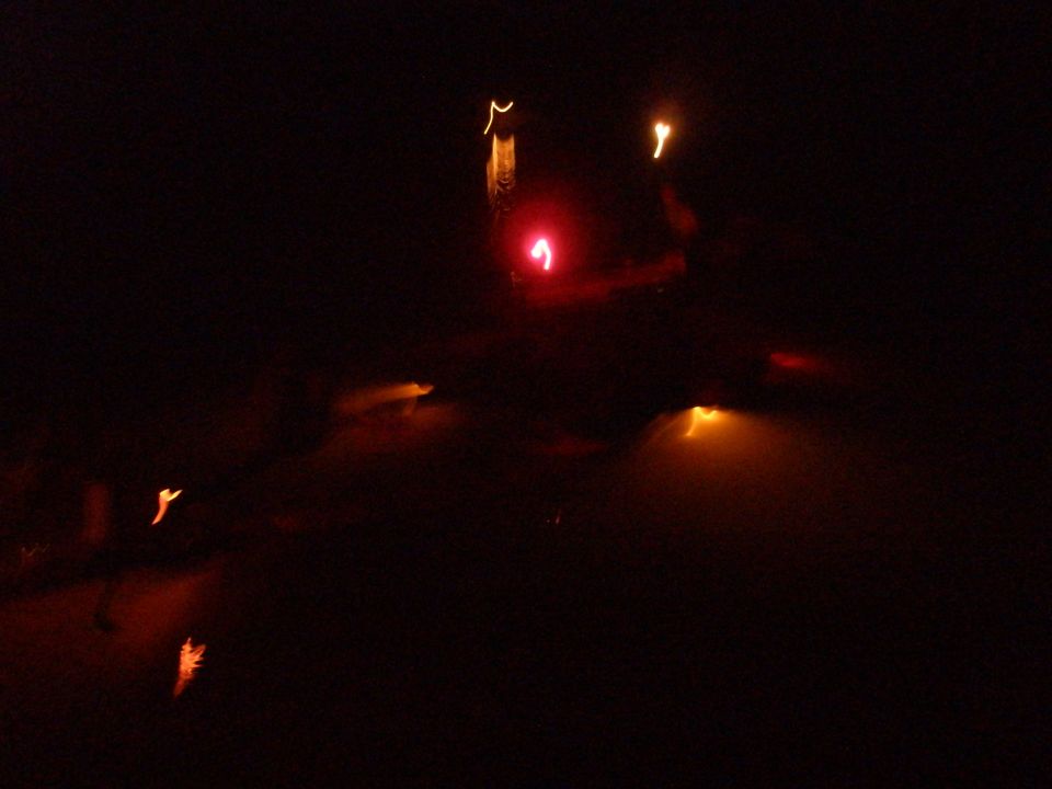 Red traffic light illuminated at night with blurred orange lights in the background