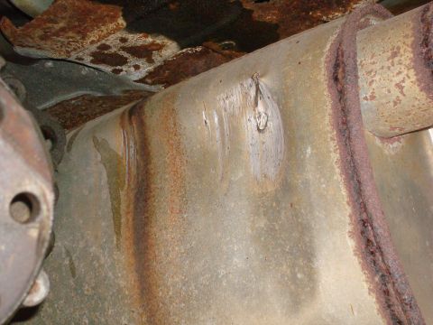 1996 Ford Bronco - Close-up view of a heavily rusted exhaust pipe and associated undercarriage components.