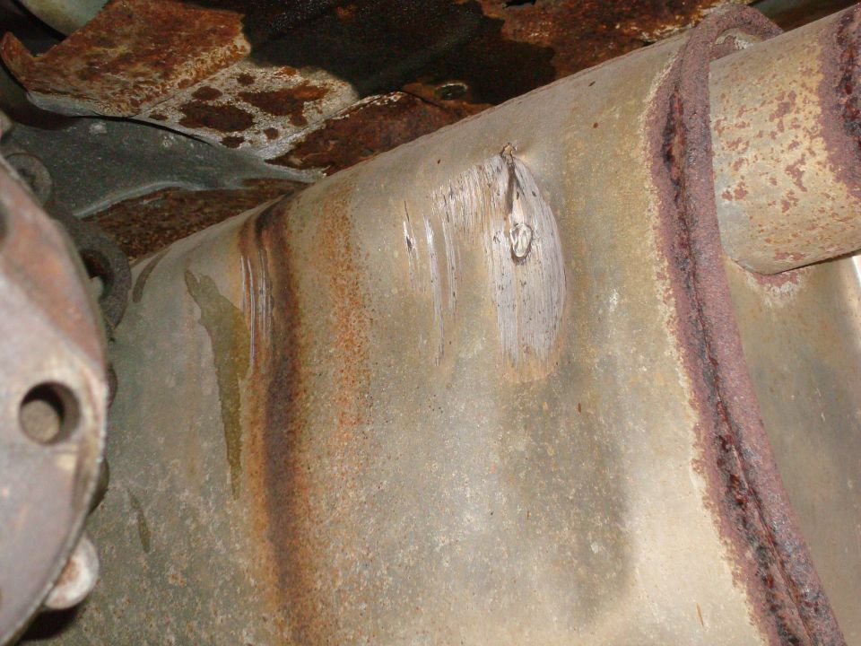 rusted exhaust pipe with visible damage and undercarriage rust
