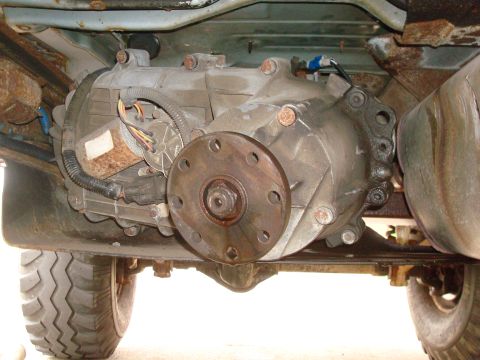 1996 Ford Bronco - The transfer case and driveshaft flange are visible from underneath the vehicle, showing mechanical components and wiring.