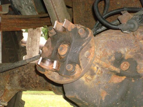 1996 Ford Bronco - Close-up of a rusty rear axle hub and suspension components, showing signs of wear and damage.