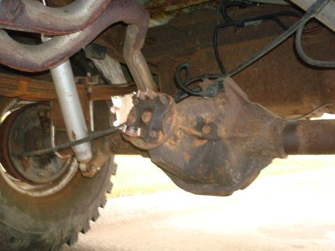 1996 Ford Bronco - Underside view of a vehicle's rear axle and suspension system, showing rust and wear.