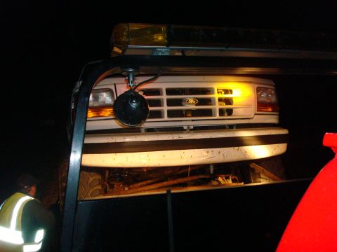 1996 Ford Bronco - A white Ford truck's front end is visible as it is towed at night.