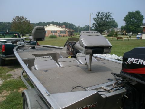 1998 Chevrolet Silverado 1500 - A bass boat with multiple seats and a Mercury outboard motor is parked next to a pickup truck in a grassy yard.