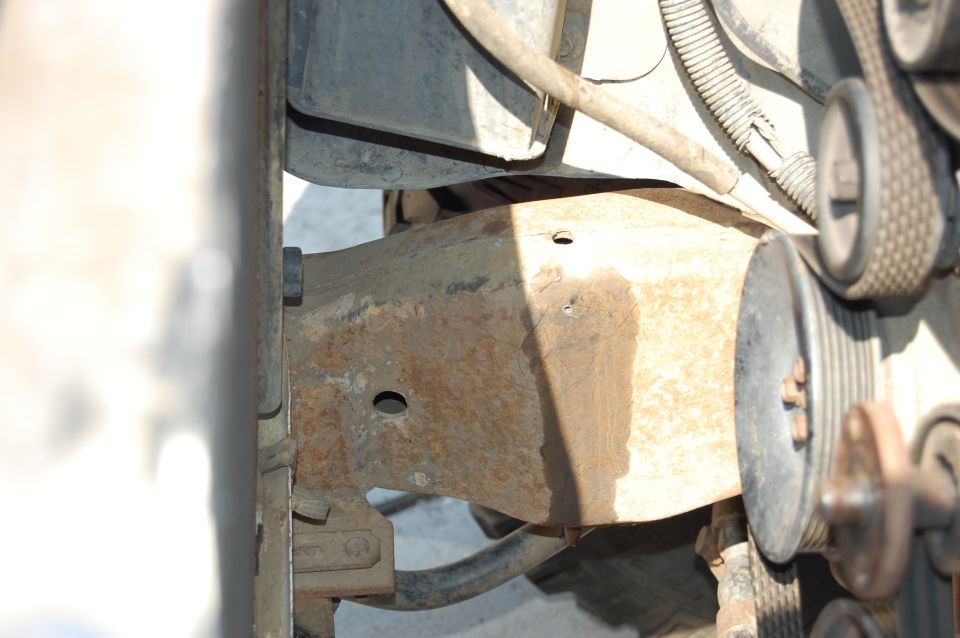 Close-up of rusty steel bracket and belt pulleys in an engine compartment