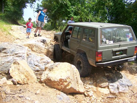 1992 Jeep YJ - Jeep Cherokee XJ tackling a difficult off-road obstacle on a sunny day.