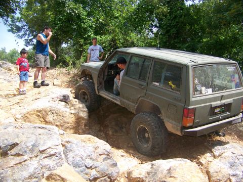 1992 Jeep YJ - A Jeep Cherokee XJ is shown tackling a challenging off-road obstacle with spectators observing the action.
