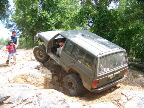 1992 Jeep YJ - A Jeep Cherokee XJ navigates a challenging rocky trail with two onlookers.