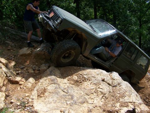 1992 Jeep YJ - Jeep Cherokee XJ tackling a challenging rocky off-road course with a person assisting from outside.