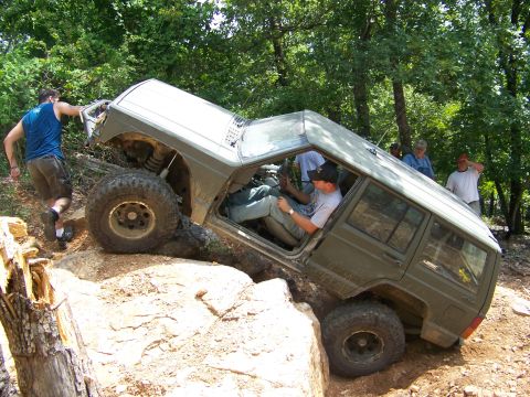 1992 Jeep YJ - A 1992 Jeep Cherokee XJ tackles a challenging off-road obstacle, with onlookers observing the action.