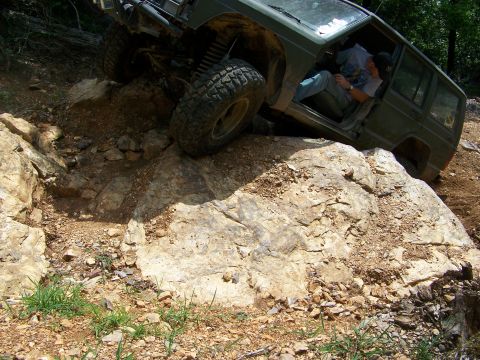 1992 Jeep YJ - A green Jeep Cherokee XJ navigates a challenging rocky terrain, with its driver seated inside.
