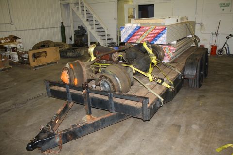 1985 Ford F-350 - A trailer carries axles and construction materials within an industrial building.