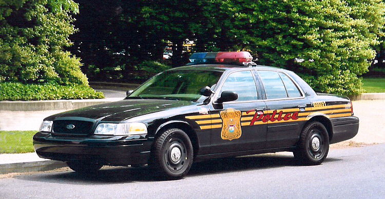 Black Crown Victoria police car with gold stripe and badge decal, front three-quarter view