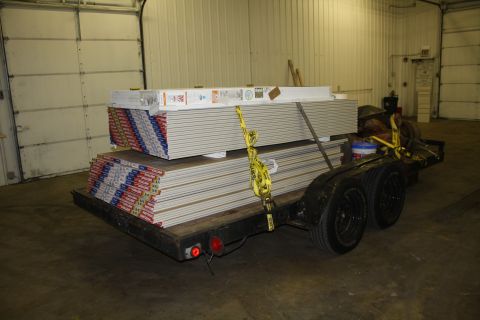 1985 Ford F-350 - Trailer carrying drywall sheets is parked inside a garage with a large overhead door.