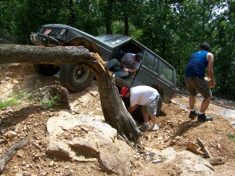 1992 Jeep YJ - A Jeep Cherokee XJ is stuck on a fallen tree while navigating a difficult off-road trail.