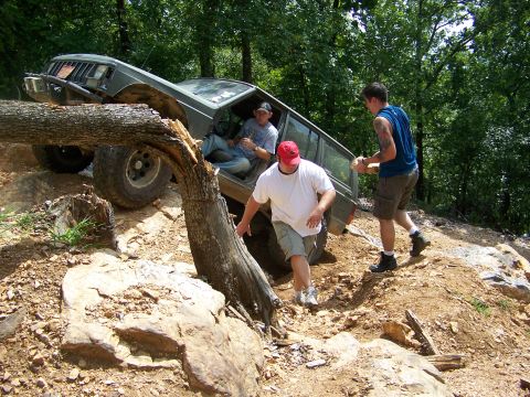 1992 Jeep YJ - People assist a Jeep Cherokee XJ as it attempts to clear a fallen tree on a challenging off-road trail.