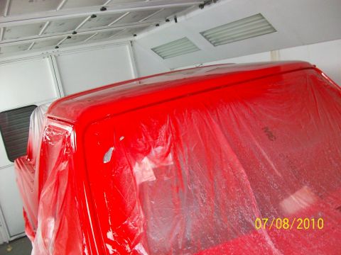 1985 Ford Bronco - A red vehicle's roof is covered in plastic sheeting inside a paint booth, with the date 07/08/2010 visible on the sheeting.