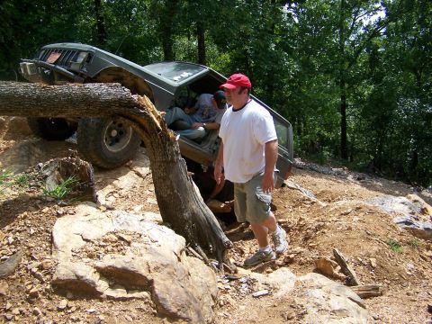 1992 Jeep YJ - A Jeep Cherokee XJ is shown attempting to traverse a difficult off-road obstacle with a fallen tree in the foreground.