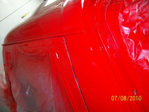 1985 Ford Bronco - A red vehicle body is partially covered in masking tape, showing a close-up of its construction.