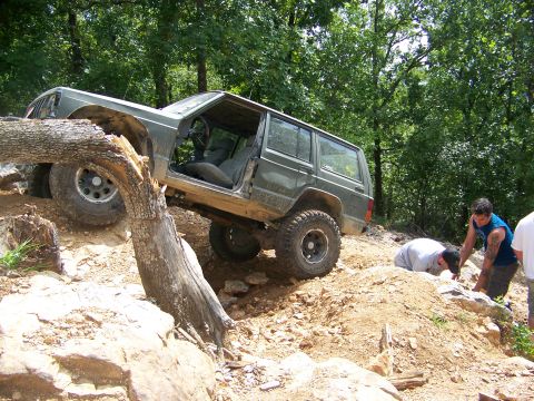 1992 Jeep YJ - This Jeep Cherokee XJ is navigating a difficult off-road trail with assistance from onlookers.