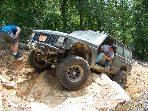 1992 Jeep YJ - A Jeep Cherokee XJ navigates a rocky trail with a person assisting from outside.
