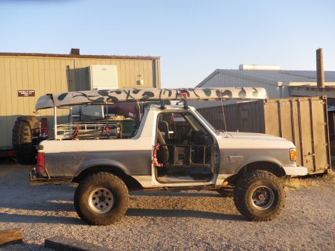 1991 Ford Bronco - This modified Ford Bronco, likely from the early 1990s, is equipped for outdoor adventure with canoes on its roof.