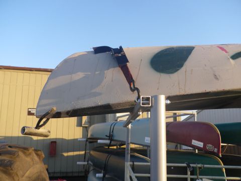 1991 Ford Bronco - Several canoes are stored on a rack, with one being fastened down by a strap and hook.