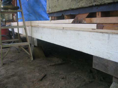1989 Ford Bronco - A construction scene shows a ladder leaning against a structure covered by a blue tarp, with exposed wooden beams and dirt ground.