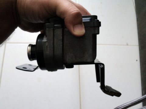 2001 Mercury Grand Marquis - A cruise control module is held by a hand, showing its metallic and plastic components and a black mounting bracket.