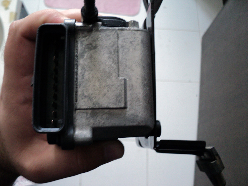 Hand holding a used aluminum-cased control module with multi-pin connector