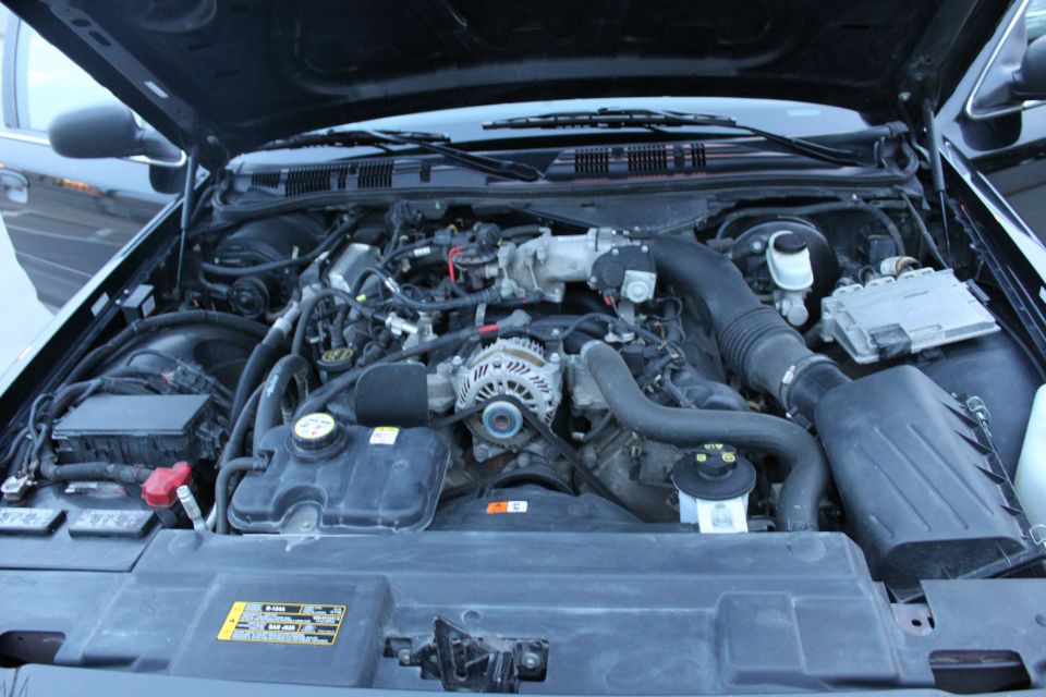 Ford V8 engine bay with air box, alternator, coolant reservoir and battery under an open hood