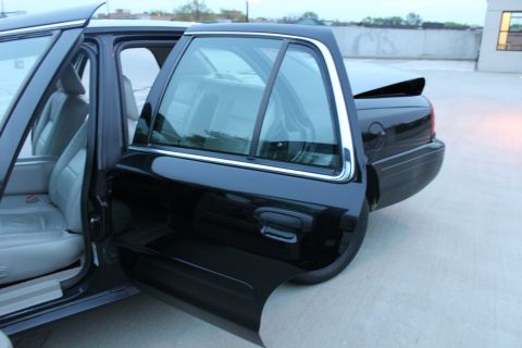 2007 Ford Crown Victoria - The side profile of a black sedan reveals its interior and rear section with the doors ajar.