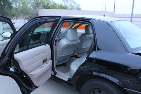 2007 Ford Crown Victoria - Driver-side doors of a black full-size sedan open wide, showing the gray front bucket seats with headrests, gray rear door panel with map p…