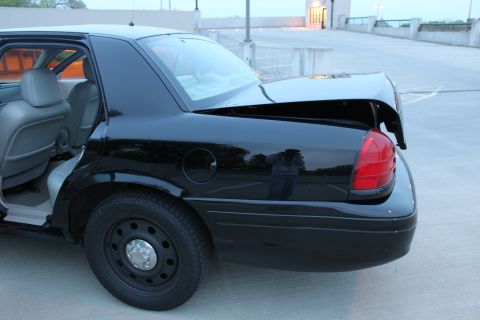 2007 Ford Crown Victoria - Rear three-quarter view of a black full-size sedan with the trunk lid raised and doors open, showing the round fuel door, tall red tail lam…